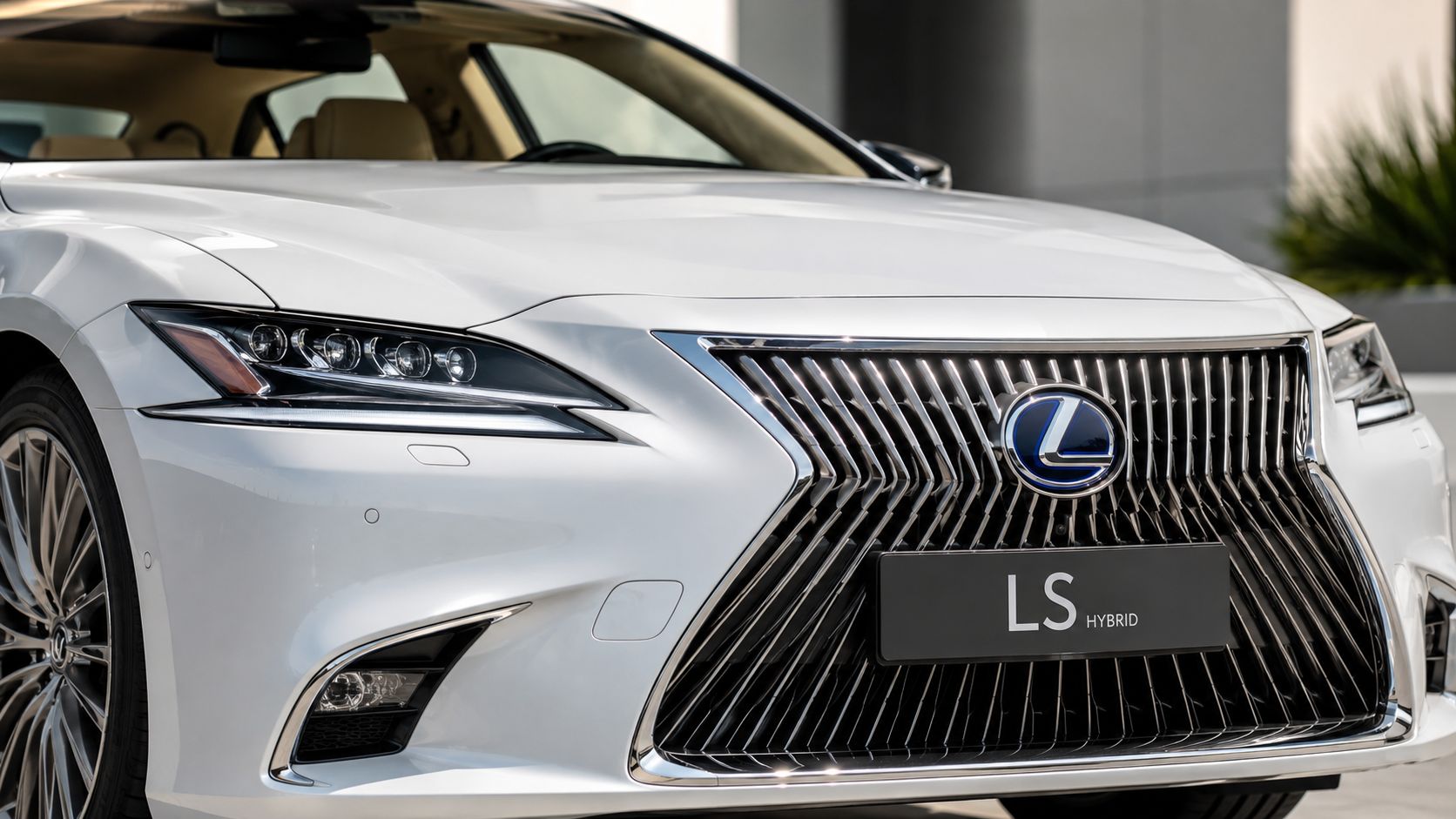 A close-up shot of the front grille and headlight of a white Lexus LS Hybrid luxury car.