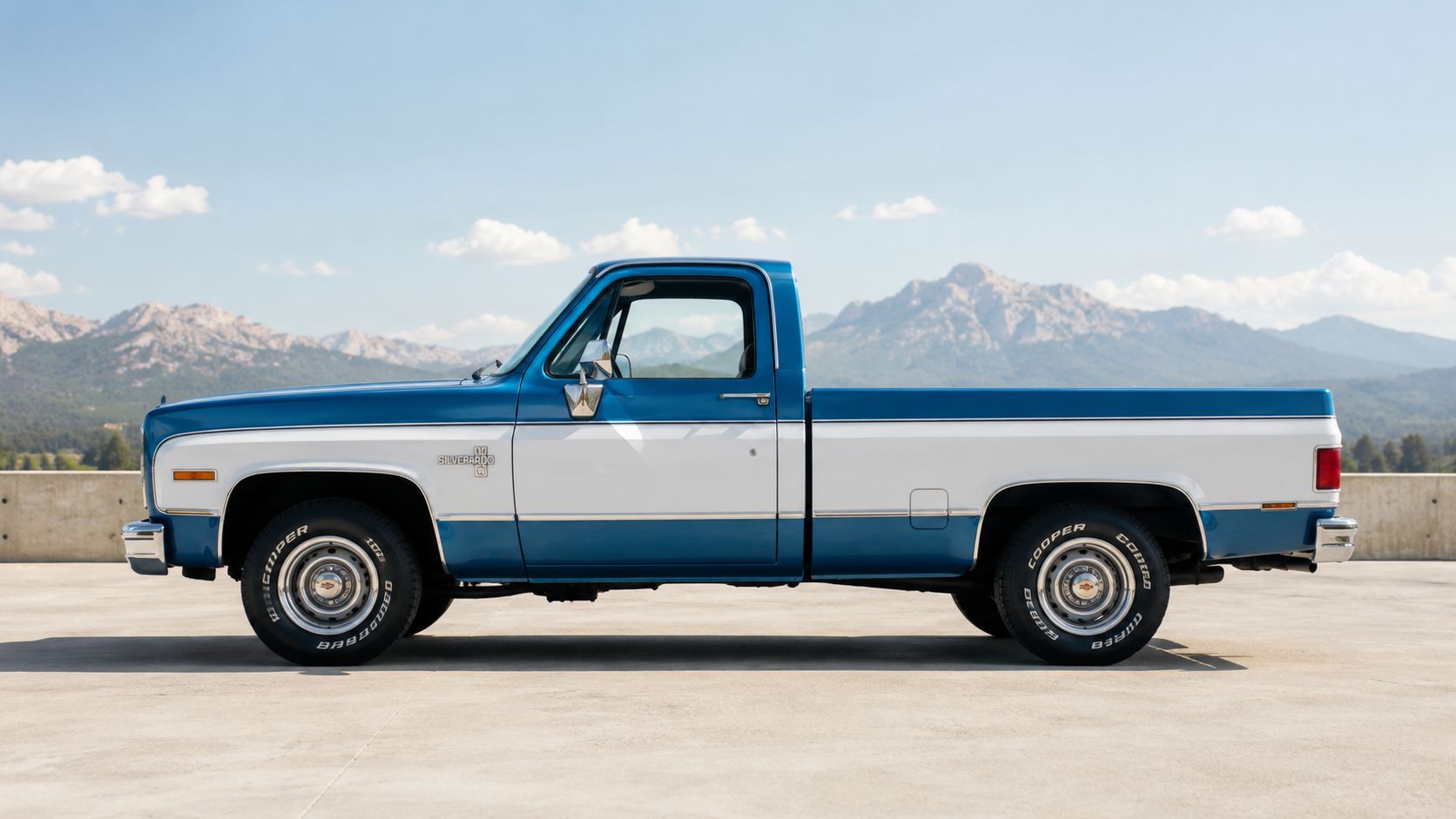 A classic blue and white Chevrolet Silverado regular cab pickup truck parked on a concrete lot.